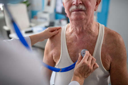 Close-up of unrecognizable senior man being checked by his doctor in doctors office.の写真素材