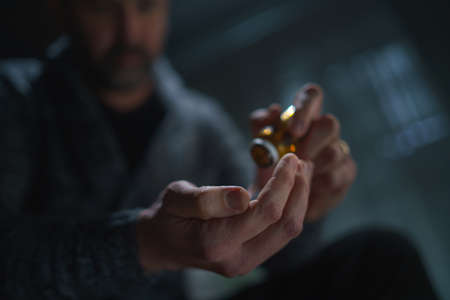 Blurred man taking drug pill on dark background, mental health concept.