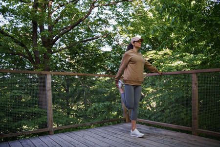 Mid adult woman doing exercise outdoors on terrace of tree house, weekend away and digital detox.