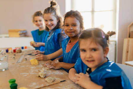 Group of little kids working with pottery clay during creative art and craft class at school.の写真素材