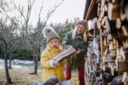 Boy with Down syndrome working in garden in winter with his grandmother.