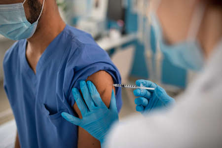 Close-up of doctor getting vaccine from his colleague.