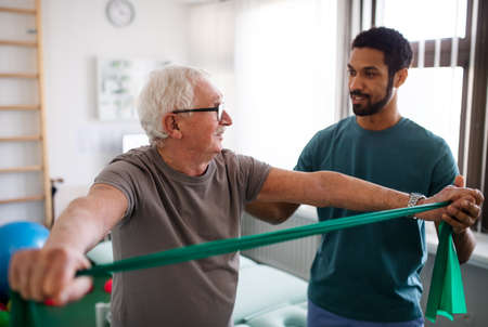 Young physiotherapist exercising with senior patient in a physic roomの写真素材