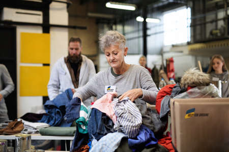 Volunteers sorting out donated clothes for the needs of Ukrainian migrants, humanitarian aid concept.の写真素材