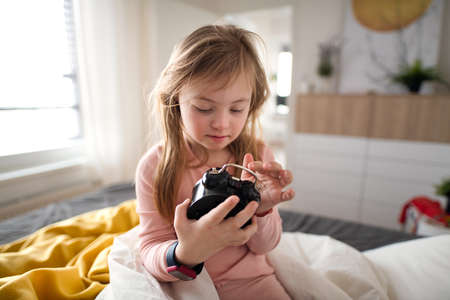 Little girl with Down syndrome playing with alarm clock at home.の写真素材
