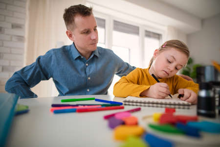 Father with his little daughter with Down syndrome learning at home.の写真素材
