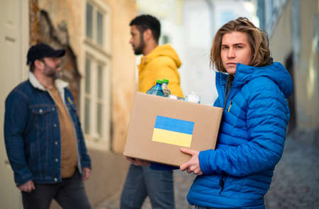 Team of volunteers collecting boxes with Humanitarian aid for Ukrainian immigrants in street
