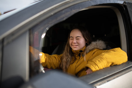 Young woman with Down syndrome driving a car and smiling.