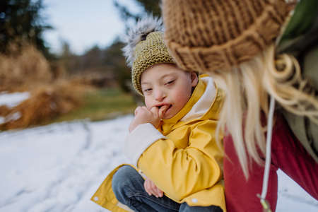 Boy with Down syndrome with his mother playing with snow in garden.の写真素材