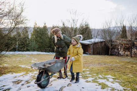 Boy with Down syndrome working in garden in winter with his grandmother.の写真素材