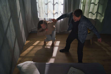 Scared woman being abused by her husband at home.の写真素材