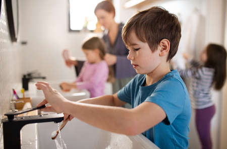 Mother with three little children in bathroom, morning routine concept.の写真素材