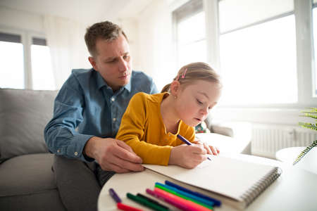 Father with his little daughter with Down syndrome learning at home.