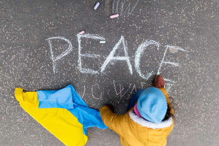 Top view of little girl writing peace with chalk. Protest against Russian invasion of Ukraine.の写真素材
