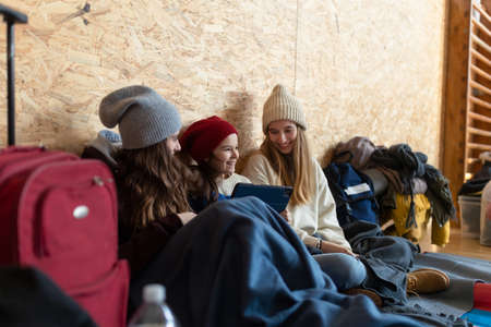 Happy Ukrainian war refugees in temporary shelter and help center, using tablet.