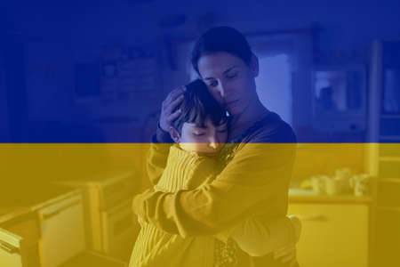Double exposure of frustrated mother hugging her daughter and Ukrainian flag.の写真素材