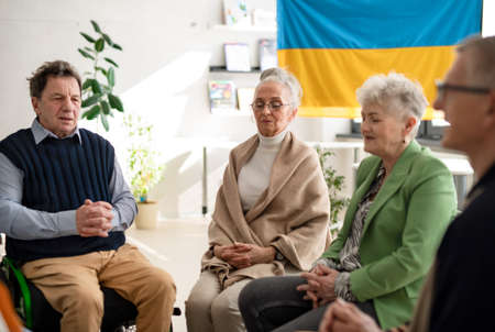 Group of seniors praying for Ukraine together in church community center.の写真素材