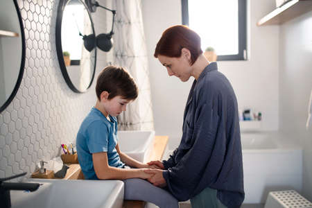 Mother consoling her little upset son in bathroom at home.の写真素材