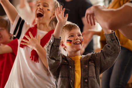 Young German football fans celebrating their teams victory at stadium.の写真素材