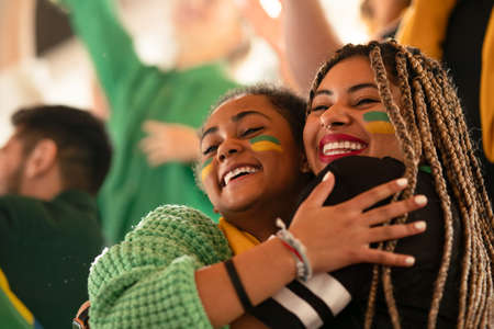 Brazilian young sisters football fans celebrating their teams victory at stadium.の写真素材