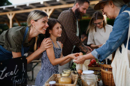 Happy woman buying organic eggs outdoors at local family farmers market.の写真素材