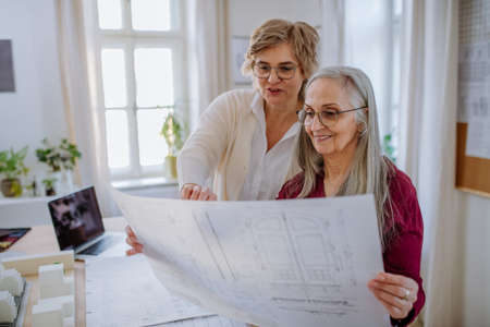 Mature women architects looking at blueprints together in office .の写真素材