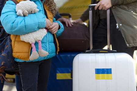 Close-up of Ukrainian immigrants with luggage waiting at train station, Ukrainian war concept.の写真素材