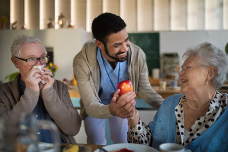 Smiling elderly woman and man enjoying breakfast in nursing home care center.
