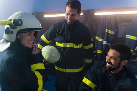 Happy firefighters men and woman talking after action indoors in fire stationの写真素材