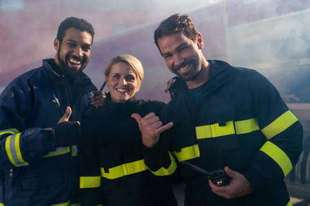 Low angle view of firefighters crew on action with fire station and truck in backgroundの写真素材