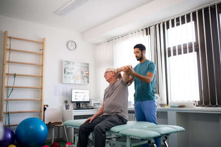 Young physiotherapist exercising with senior patient in a physic roomの写真素材