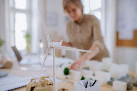 Senior woman eco architect with model of modern bulidings working in office.の写真素材