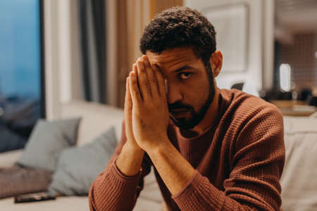 Portrait od depressed young African - American man, looking at camera.