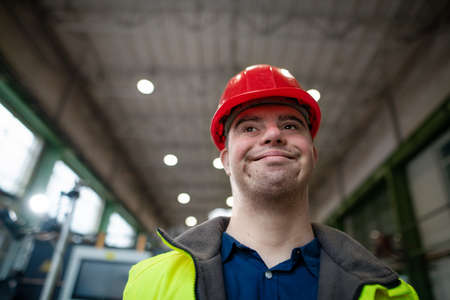 Young man with Down syndrome working in industrial factory, social integration concept.の写真素材