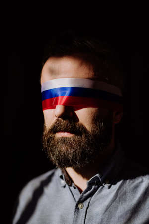 Man with Russian flag blindfold on black background, Russian propaganda closed peoples eyes concept.の写真素材