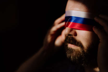 Man with Russian flag blindfold on black background, Russian propaganda closed peoples eyes concept.の写真素材