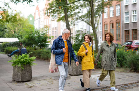 Portrait of happy grandparents with preteen grandddaughter walking together ourtdoors in town street