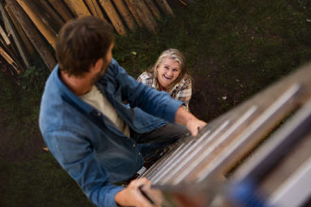 High angle view of mature man climbing up the ladder looking at his wifeの写真素材
