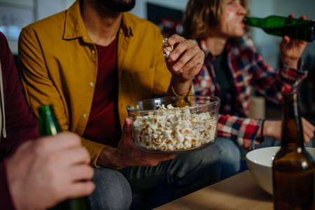 Close-up of football fans friends watching match and eating popcorn.の写真素材