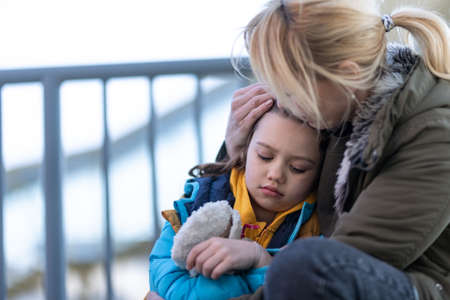 Ukrainian immigrants mother with daughter with luggage waiting at train station, Ukrainian war concept.の写真素材