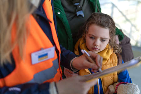 Volunteer filling form for Ukrainian refugees at train station.の写真素材