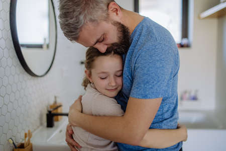 Father hugging his little daughter in bathroom.の写真素材