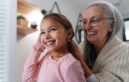 Senior grandmother and granddaughter standing indoors in bathroom, daily routine concept.の写真素材