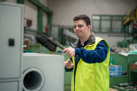 Young man with Down syndrome working in industrial factory, social integration concept.の写真素材
