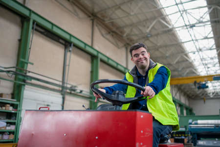 Young man with Down syndrome working in industrial factory, social integration concept.