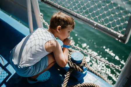 Little curious boy looking at water from motor boat.の写真素材