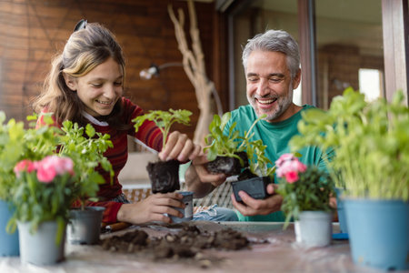 Teenage daughter helping father to plant flowers, home gardening conceptの写真素材