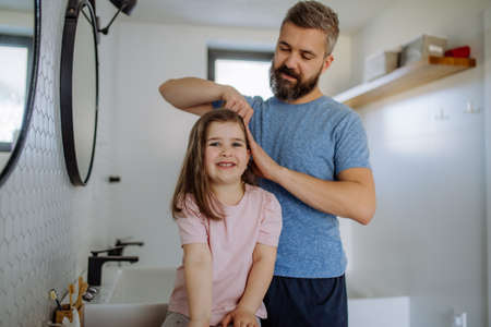 Father brushing his little daughters hair in bathroom, morning routine concept.の写真素材