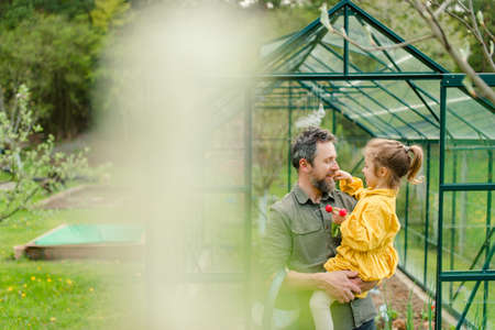 Father with his little daughter bonding in front of eco greenhouse, sustainable lifestyle.の写真素材