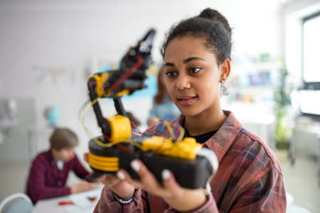 College student holding her robotic toy at robotics classroom at school.の写真素材